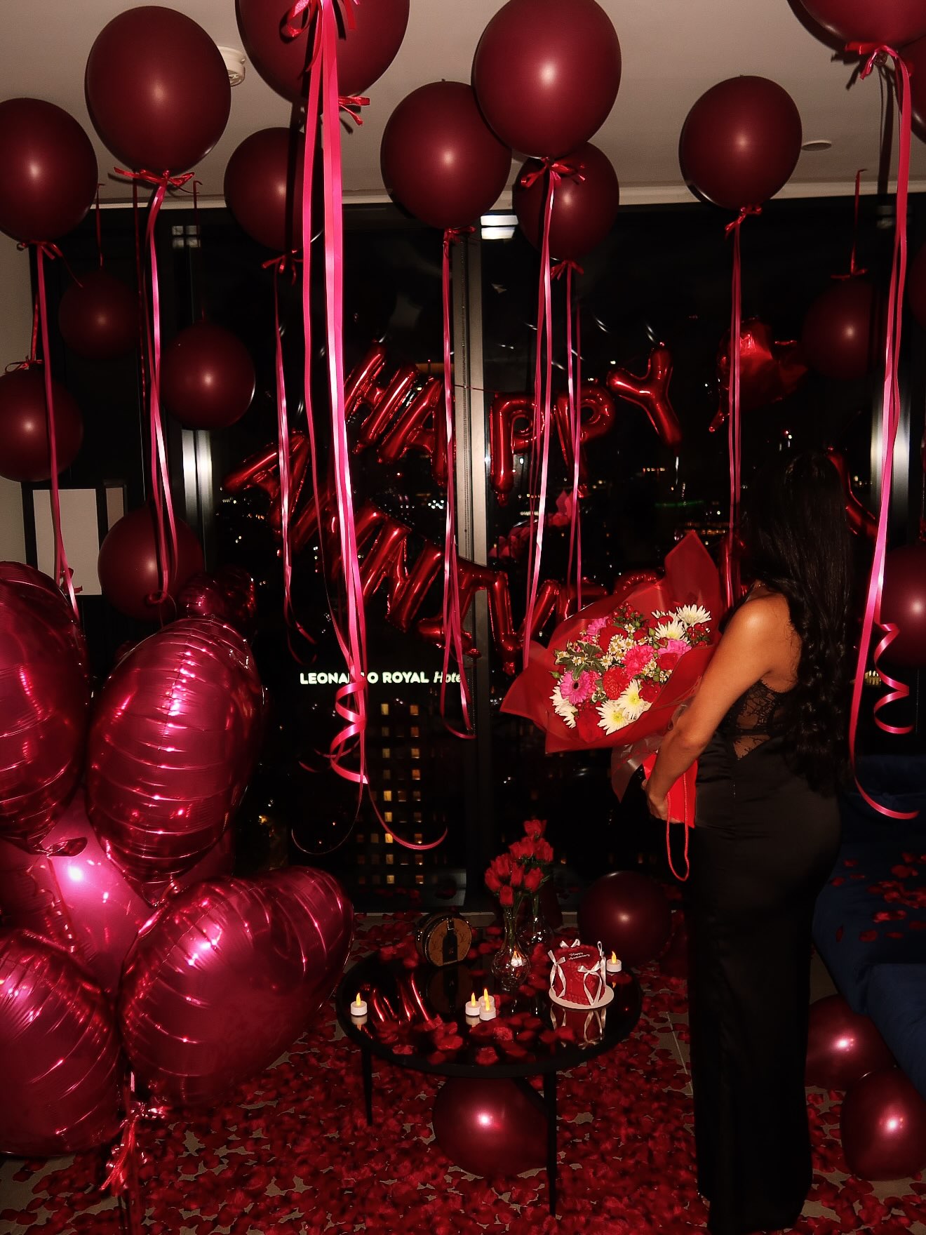 A romantic red anniversary room with a bouquet and rose petals